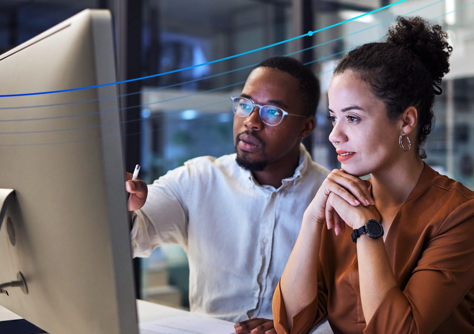 Two colleagues reviewing information together on a computer monitor